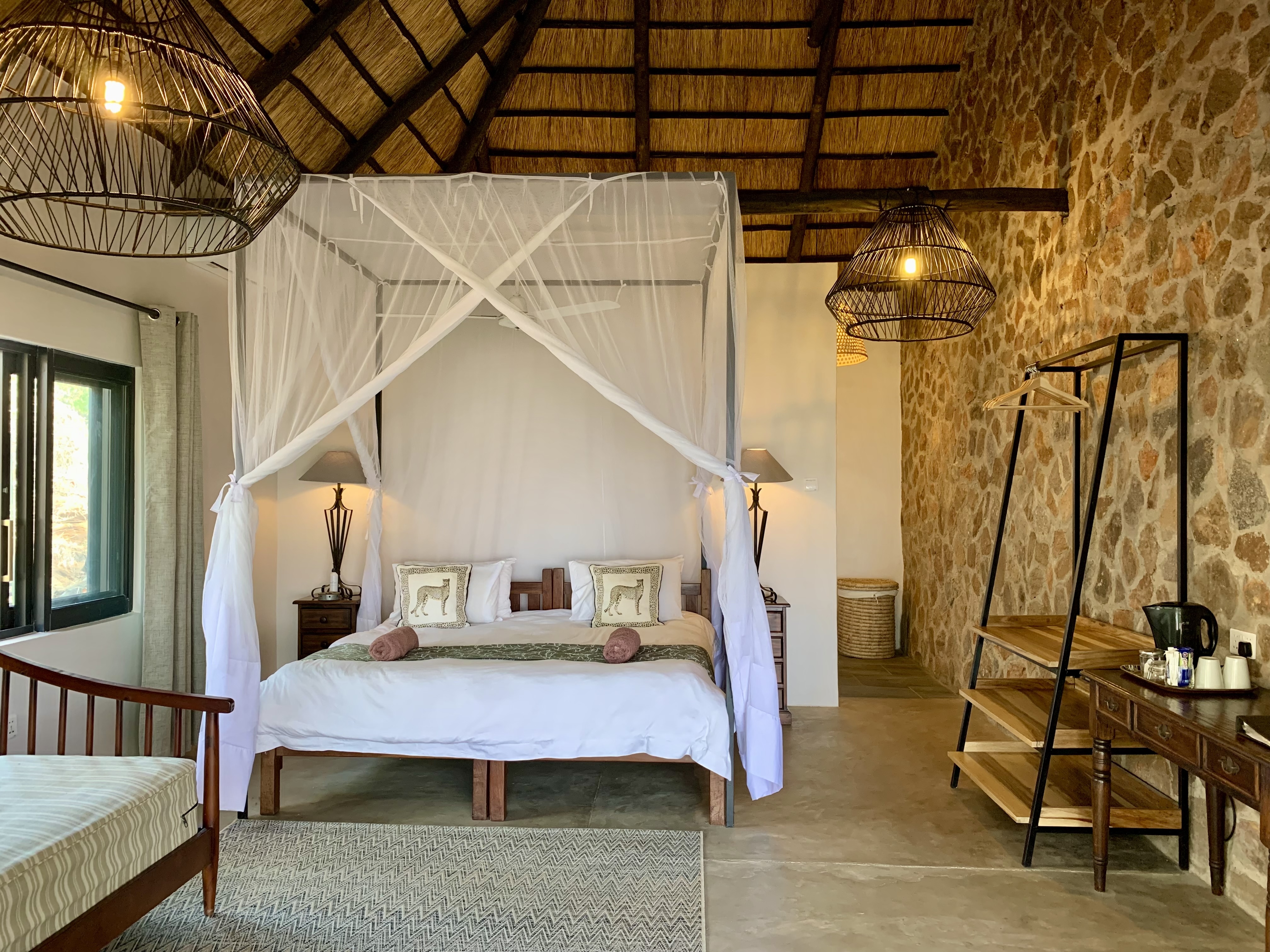 Thatched room with four-poster bed and mosquito net
